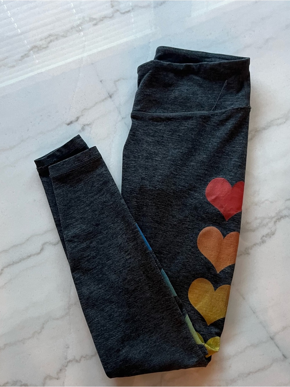 Soft charcoal gray leggings with colorful rainbow heart prints along side.